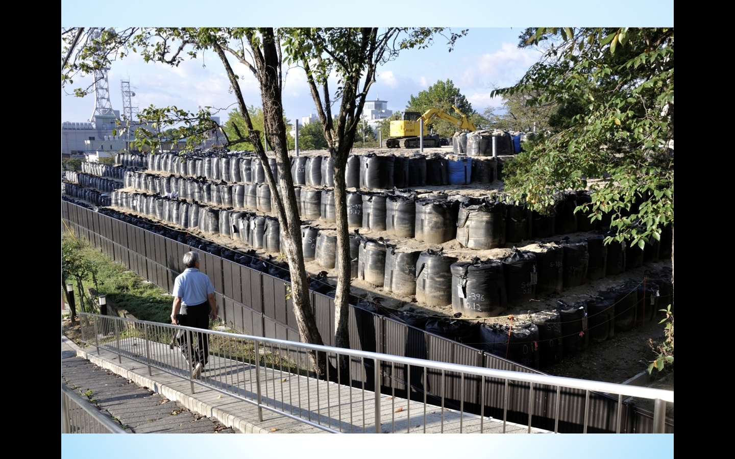 Man walks by "temporary" storage area for radioactive decontamination waste in Fukushima. ©2014, Yugi Kaneko