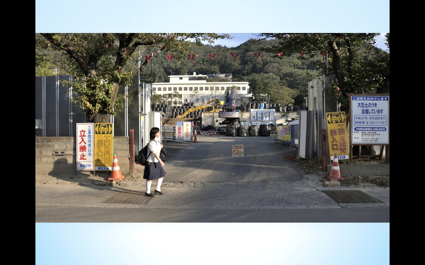 Fukushima schoolgirl walks past incineration facility for radioactive waste.
